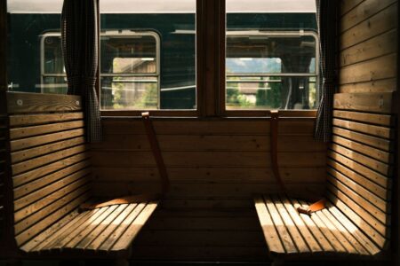 Tomt träklätt tågfack med gardiner och bänkar i varmt solljus